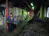 Сотрудник котельной закидывает уголь в один из двух работающих котлов